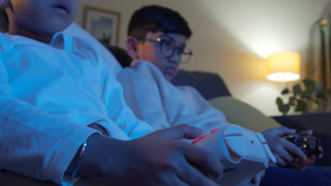Close-Up-On-Hands-Of-Two-Young-Boys-At-Home-Playing-With-Computer-Games-Console-On-TV-Holding-Controllers-Late-At-Night-4